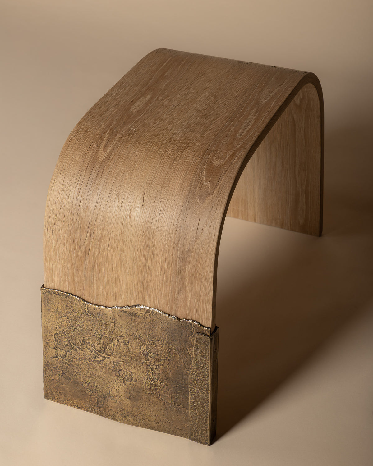 Brume bench from above, showing the curved oak surface meeting the brass leg.