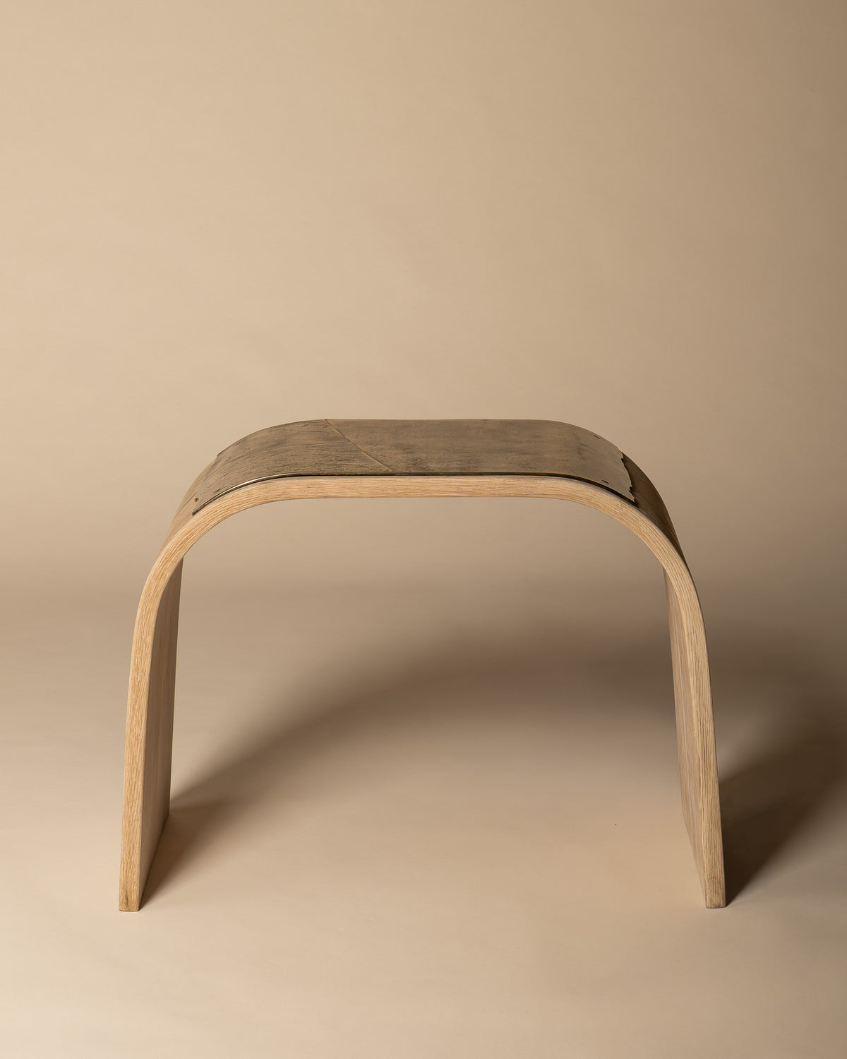 Veil bench in side profile, showing the open arch beneath its brass seat.
