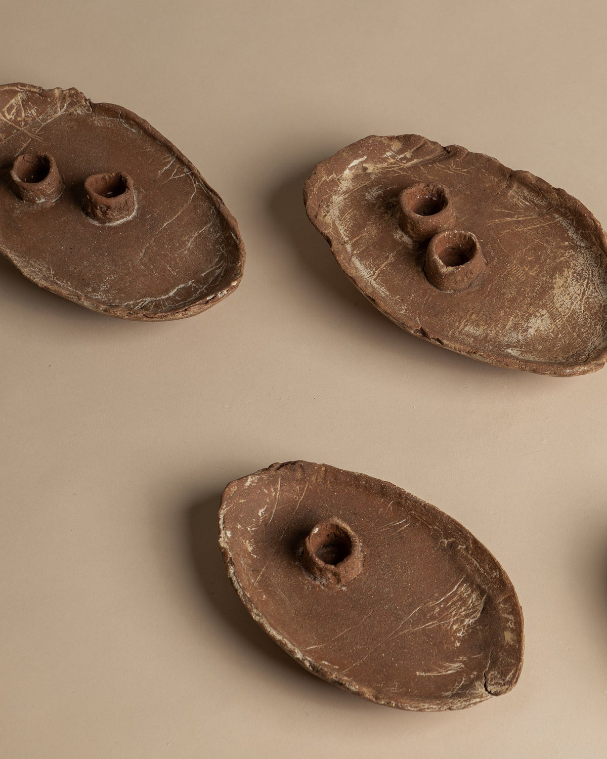 Utah Clay candlesticks viewed from above, with two complete single candlesticks showing variations in handmade shape, rim and surface; other candlesticks are partly visible. Sold individually.