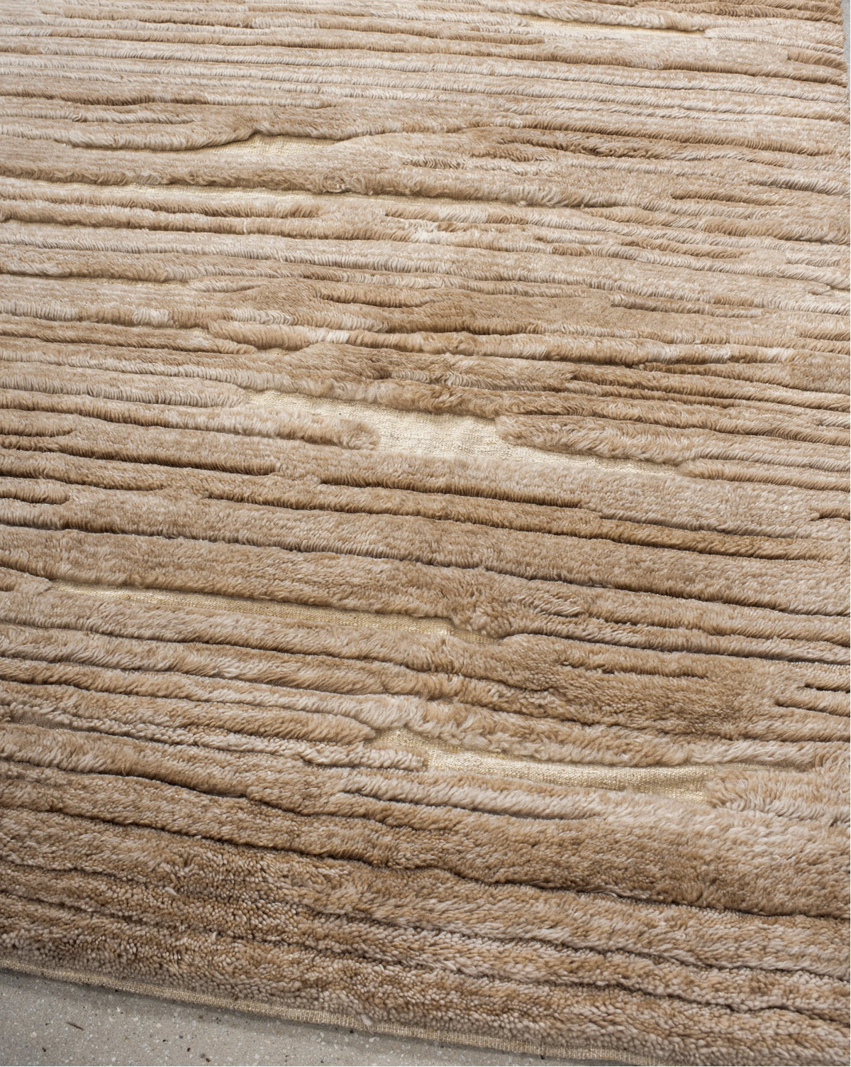 Placeholder photograph: angled view of the sand-coloured rug showing raised rows and its bound edge.