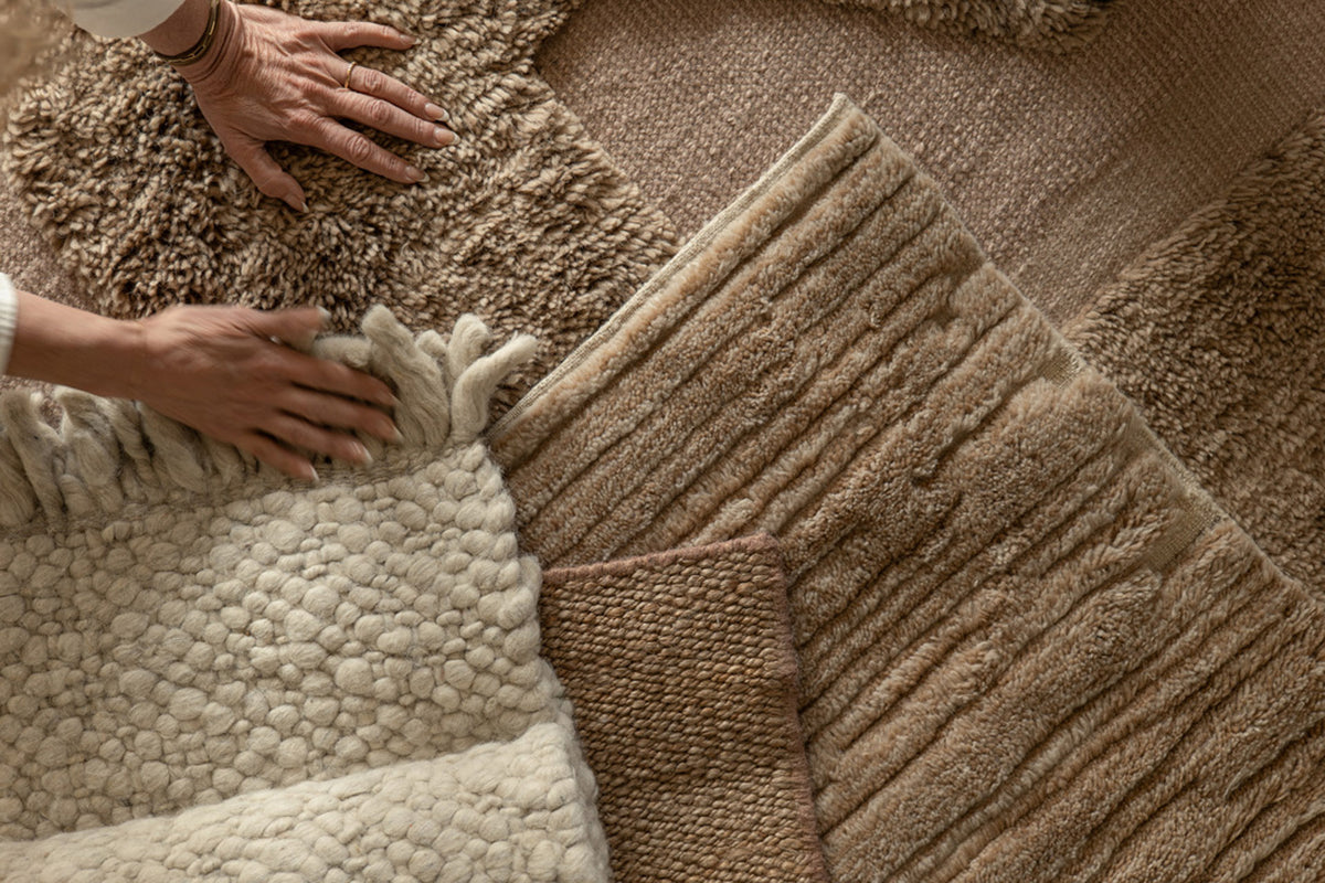 Hands arranging layered rug samples