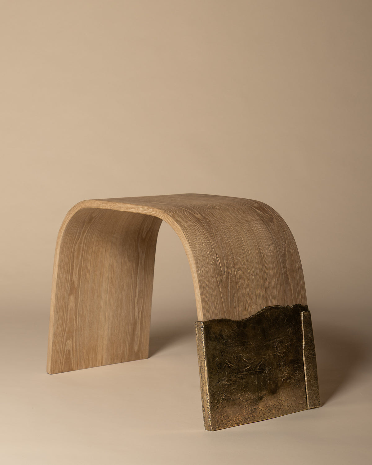 Brume bench viewed from the opposite side, showing its curved oak form and brass leg.