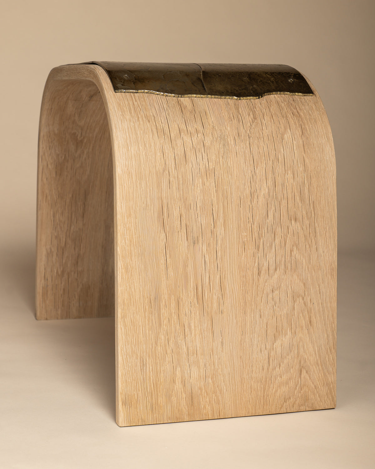 Veil bench from an elevated end angle, showing its oak grain and brass top.